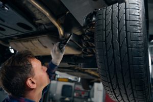 Technician inspecting a car’s suspension and undercarriage on a vehicle lift